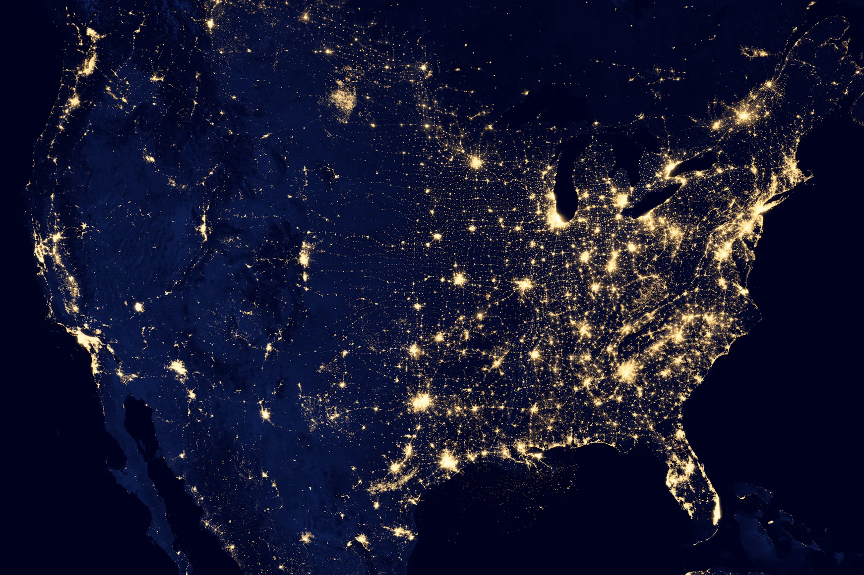 Satellite view of the United States at night, city lights against deep navy
